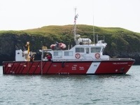 Photography of the Canadian coast guard vessel Viola M. Davidson with rocky cliff in the background