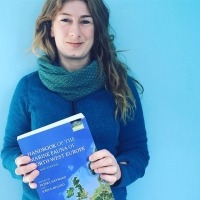 Photograph of Claire Goodwin with a textbook she has co-authored.