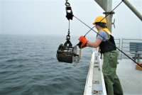 Scientist releasing large metal grab sampler from the side of the Fundy Spray.
