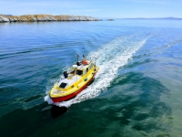 Photograph of a red and yellow boat travelling over a calm sea.