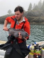 Researcher Kaleb Zelman aboard a small boat holding an Atlantic wolffish