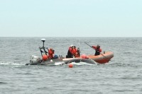 Photograph of the Campobello Whale Rescue team on a small boat trying to free an entangled right whale from ropes.