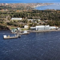 Aerial view of Saint Andrews Biological Station at the edge of the sea with St Andrews in background. Cluster of nine buildings include one large white one on the seafront.
